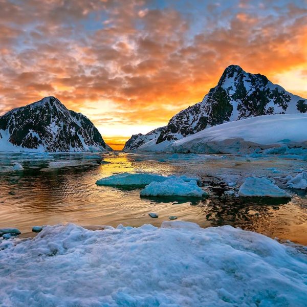 A breathtaking sunset casting vibrant hues over Antarctica’s icy landscape.