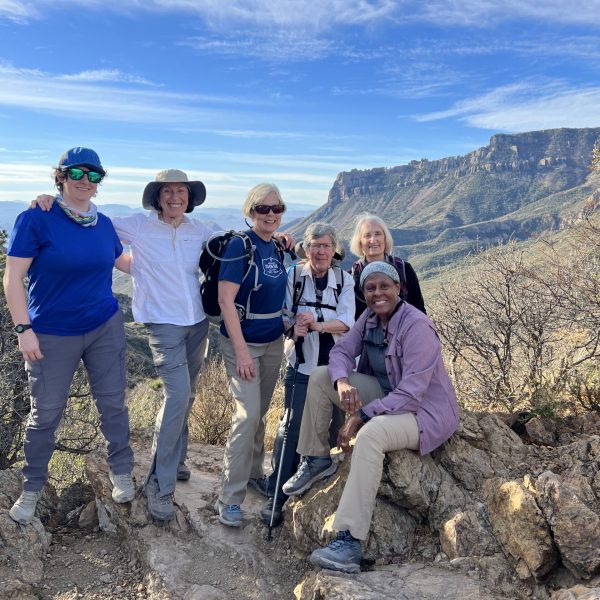A smiling group of women pose for a photo with the picturesque mountains of the Big Bend region in the background - Big Bend Exploring and Hiking - Adventures in Good Company