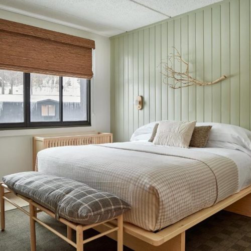 A double bed with a view of the snowy world beyond at the Bluebird Lake Placid Hotel in Lake Placid, New York