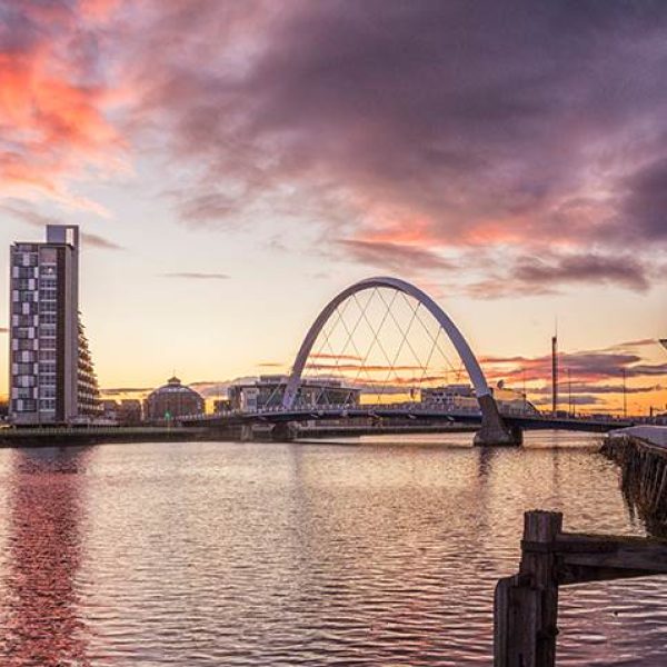 A beautiful sunset with pink and purple colors highlighting the Clyde Arc Bridge in the city of Glasglow - Scottish & Irish Highlights - Brenda Vacation