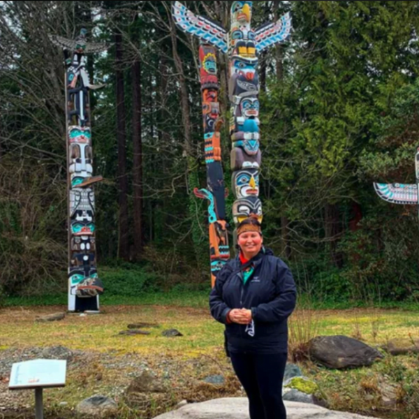 woman standing in front of totem poles - Talasay Tours