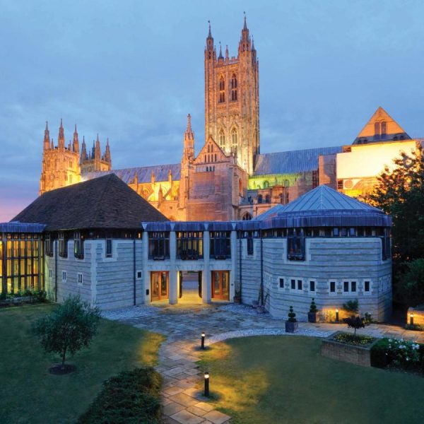 A view of the exterior of the Canterbury Cathedral Lodge in Canterbury, England, UK, at dusk—recommended by a JourneyWoman reader as a safe place for women to stay.