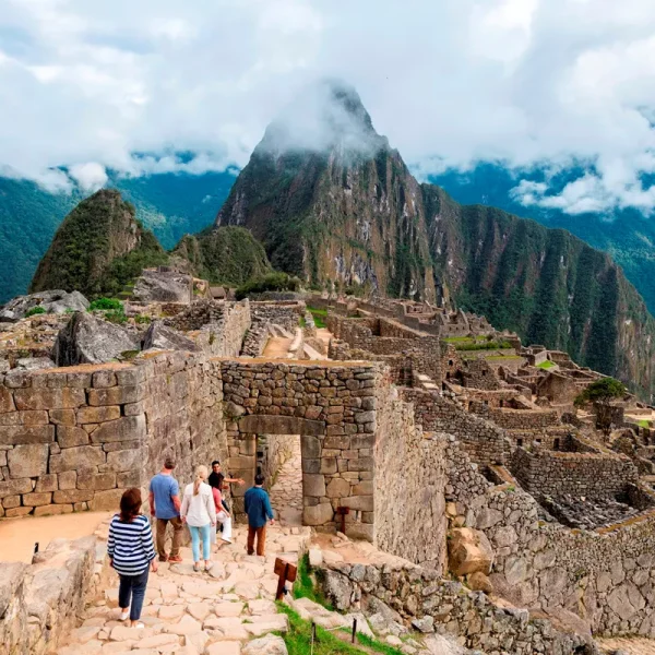 Enthusiastic group of travelers eagerly approaching the entrance to the awe-inspiring wonder of Machu Picchu, surrounded by majestic Andean peaks and mystical atmosphere - Insight Vacations