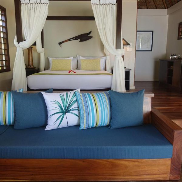 A simple queen-sized bedroom with a bench at the Paradise Cove Resort in Fiji, recommended as a safe place for women to stay by a JourneyWoman reader.