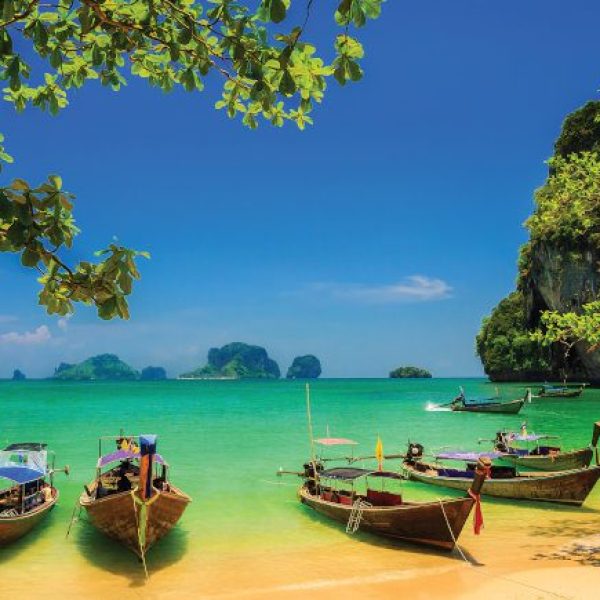 Longtail boats rest along the Phra Nang Beach, a leisure spot on the Thailand - Land of Smiles tour with Just You