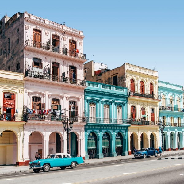 A vibrant view of Cuba's colorful streets, featuring pastel-hued buildings and a vintage car - Classic Cuba: Culture & Cuisine