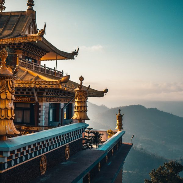 An ornate temple with gold detail overlooks the mountains in the background - Nepal Trail Running and Wellness Retreat - Run Wild Retreats