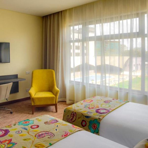 A simple twin bed room with bright yellow accents at the Tamarind Tree Hotel in Nairobi, Kenya.