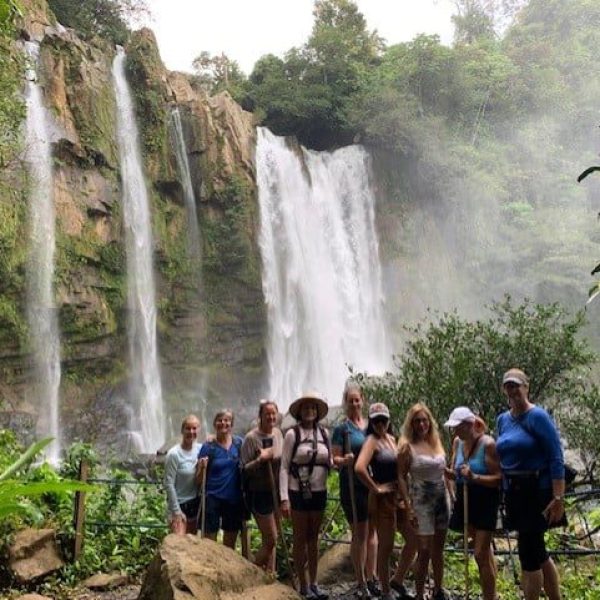 A group of tourists gaze up at a waterfall as part of the Costa Rica Jungles and beaches tour with Women Traveling the World.