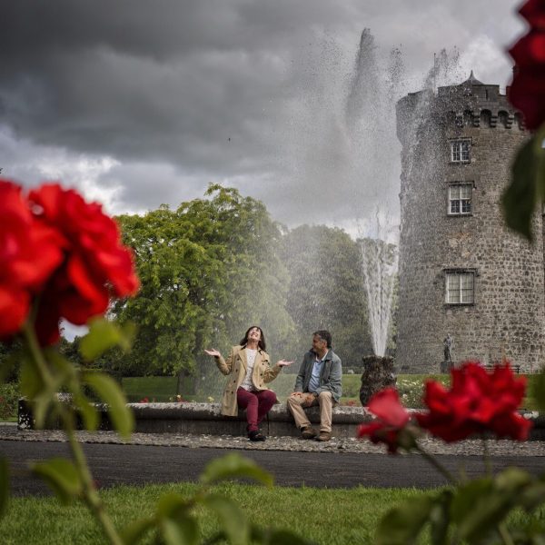a couple sitting in the fountain laughing enjoying a cloudy afternoon at Kilkenny Castle - Irish Highlights - Brendan Vacations
