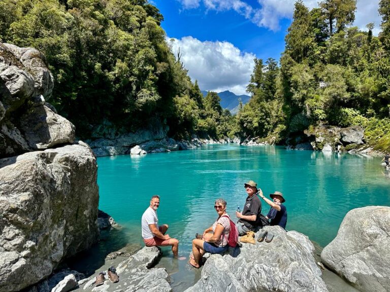 A group of women enjoying the breathtaking view of a serene lake surrounded by lush greenery and distant mountains