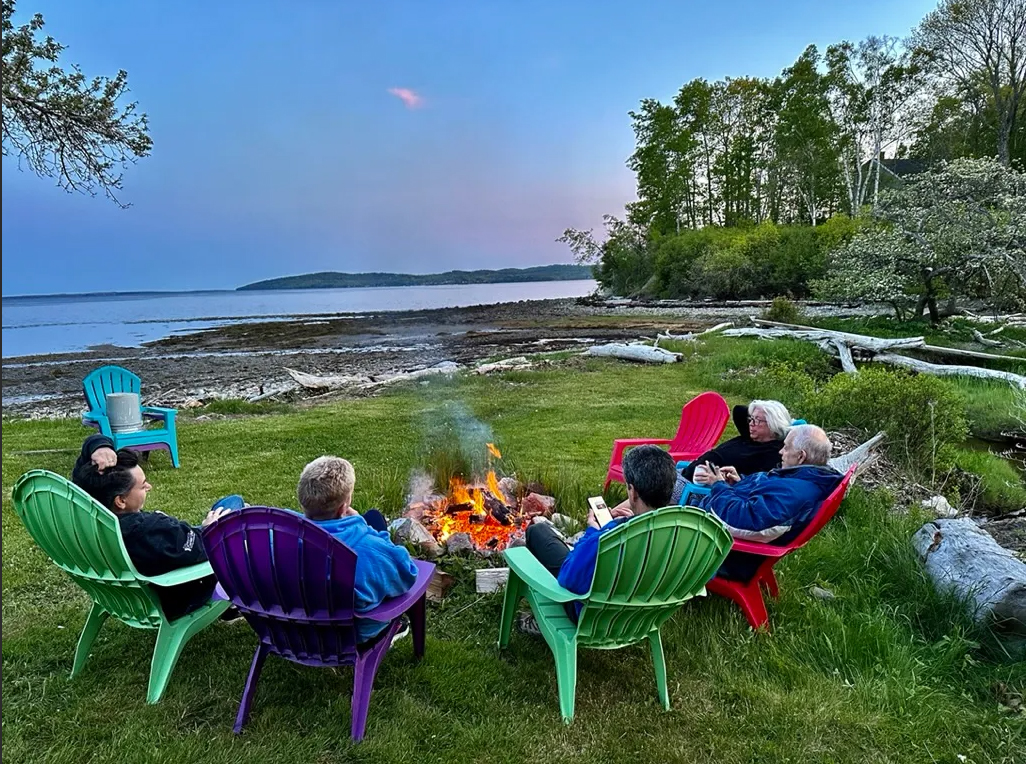 Group of women relaxing together by a cozy fire pit on a calm afternoon - Spirit of Watercolor in Maine