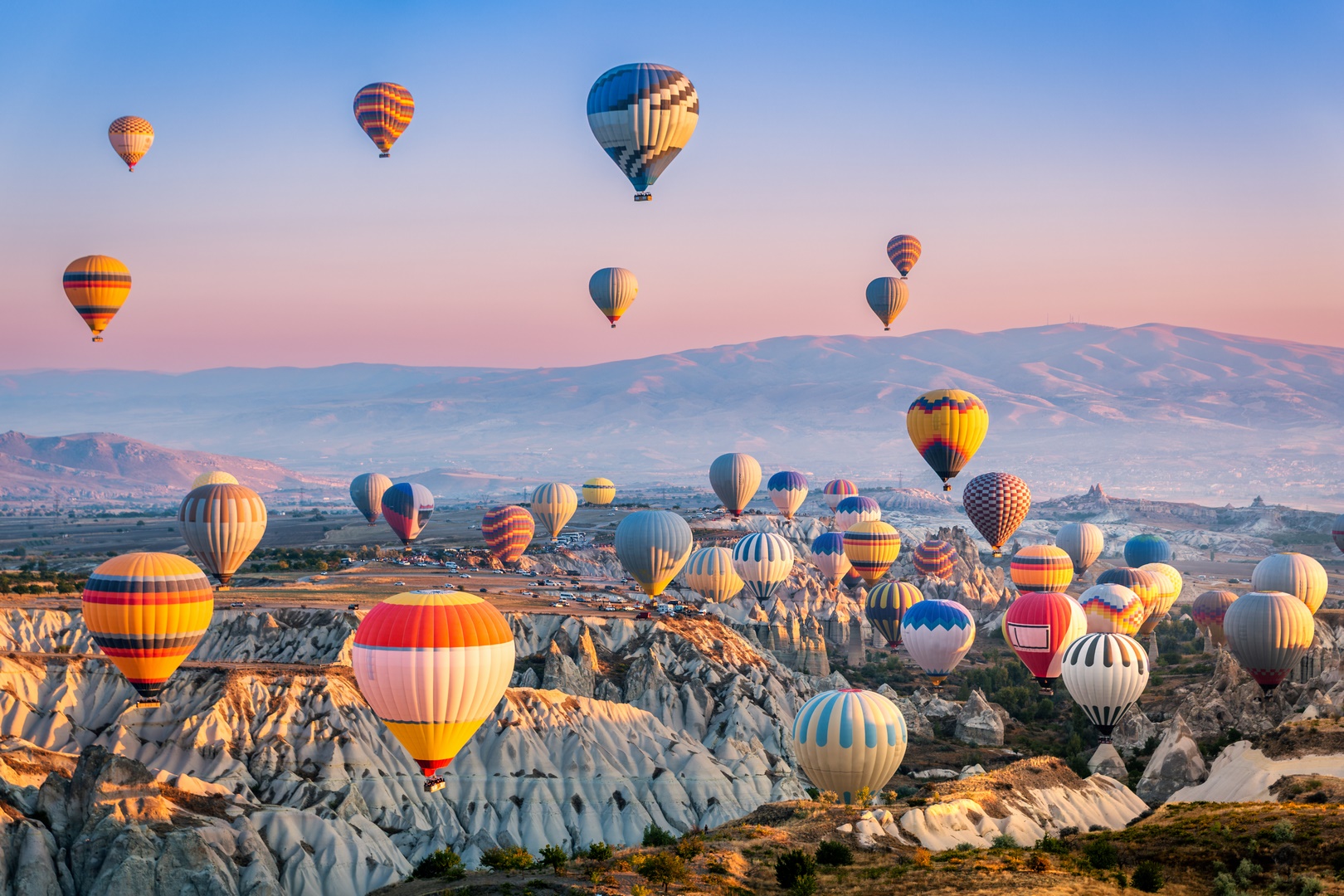 Colorful hot air balloons floating above the unique rock formations and fairy chimneys of Cappadocia - Turkish Treasures