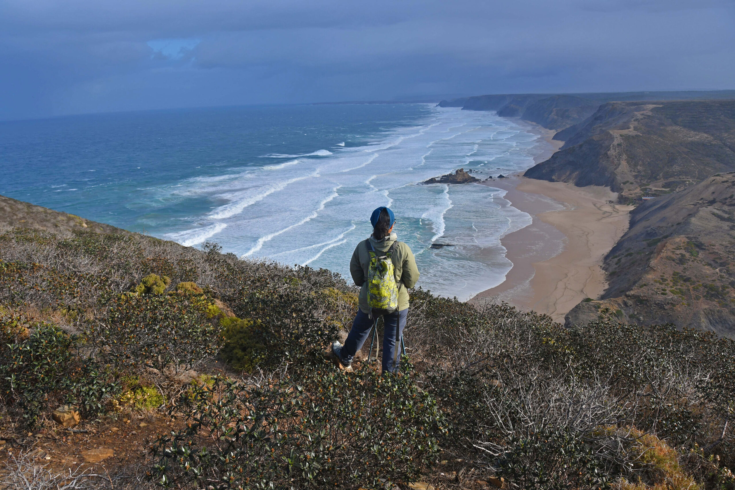 A Woman overlooking a stunning beach with dramatic cliffs in the Algarve