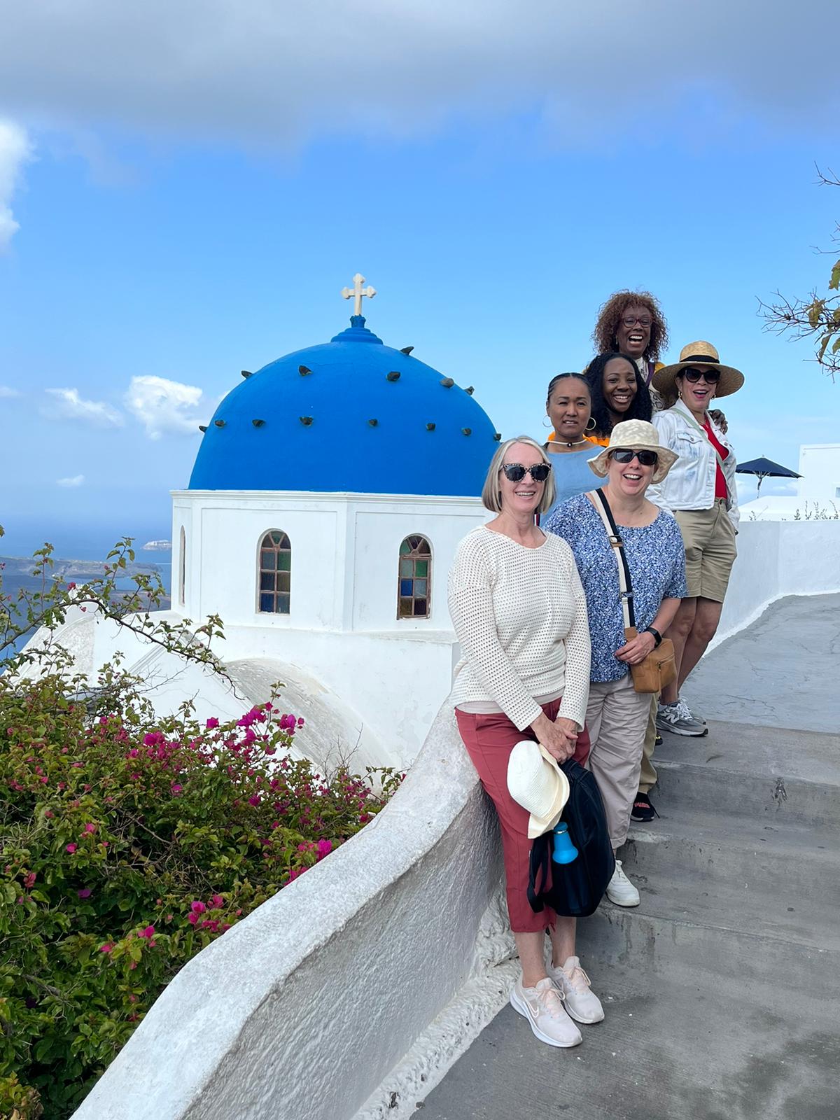 A group of people enjoying a rooftop in Santorini, surrounded by iconic blue-and-white architecture.