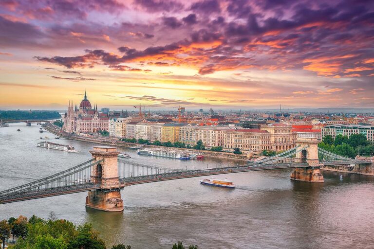 A stunning sunset over Budapest, featuring the iconic Chain Bridge and the Parliament building along the Danube River. This breathtaking view is part of the Prague, Vienna & Budapest tour, where travelers can explore the heart of Europe in style.