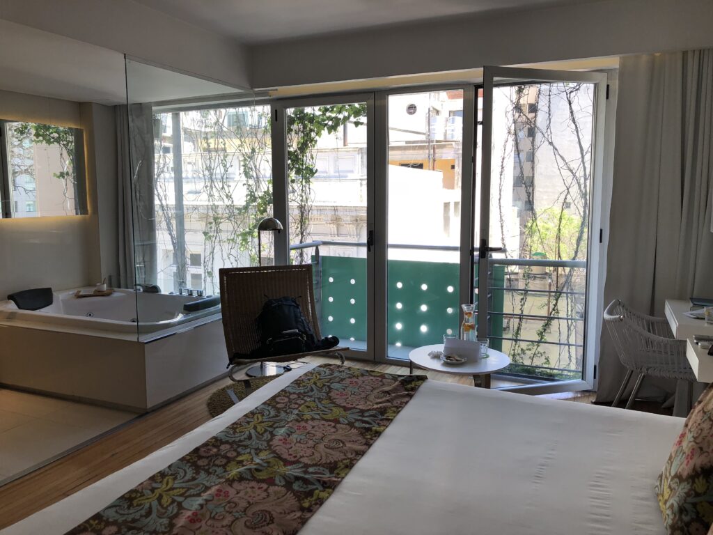 A simple bedroom with a balcony and view of the city at Casa Calma in Buenos Aires Argentina, recommended by JourneyWoman readers as a safe place for women to stay.